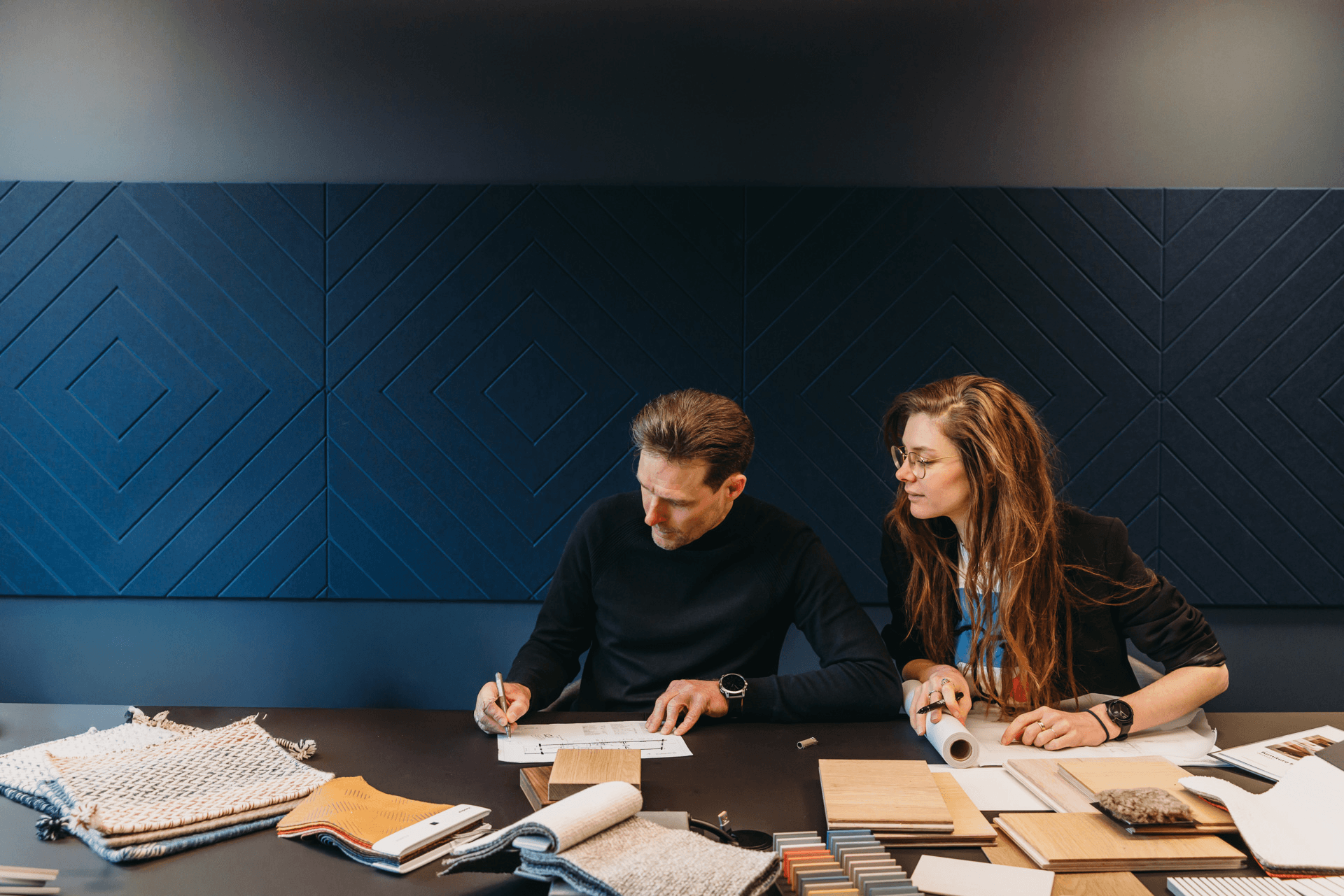 Man en vrouw aan een tafel aan het brainstormen met verschillende materialen